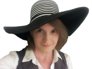 Woman with black and white striped large-brim hat, white shirt, and gray vest.